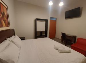 a bedroom with a white bed and a red chair at La Cabaña Hostal in Mollendo