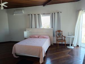 a bedroom with a bed and a chair and a window at WSL Saqua, Suite com ar, piscina, lounge, salão festas, churrasqueira, jogos, jardim, estacionamento 800m2 in Saquarema +71 photos