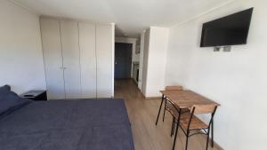 a bedroom with a bed and a table and a tv at Departamento Studio en pleno centro de Concepción in Concepción