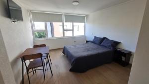 a bedroom with a bed and a table and a window at Departamento Studio en pleno centro de Concepción in Concepción
