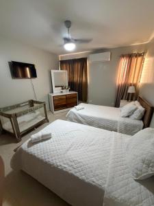 a hotel room with two beds and a television at madrigal 1-3br with parking in Santiago de los Caballeros