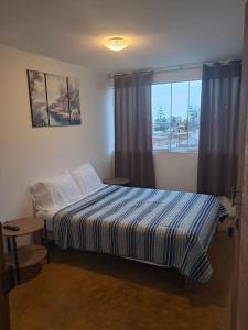 a small bedroom with a bed and a window at Kaihalulu Beach Room - Punta Hermosa in Punta Hermosa
