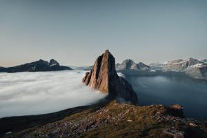 a mountain in the middle of a lake with clouds at Polar Panorama Lodge in Fjordgård