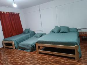 a bedroom with two beds and a red curtain at Los Colibríes del Valle in Valle Hermoso