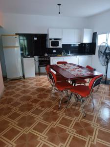 a kitchen with a table and red chairs and a kitchen with white cabinets at Los Colibríes del Valle in Valle Hermoso