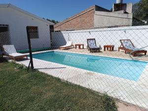 a fence next to a swimming pool with two chairs at Los Colibríes del Valle in Valle Hermoso +10 photos