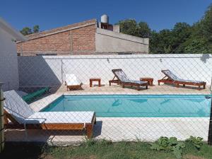 a swimming pool with chairs and a fence around it at Los Colibríes del Valle in Valle Hermoso