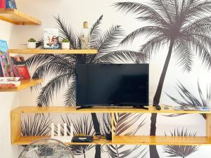 a tv on a shelf with a palm tree on a wall at Private beach access, fiber optic internet & parking in Punaauia