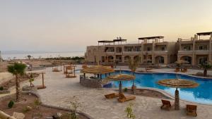 a resort with a pool and tables and umbrellas at Sina Cave in Dahab