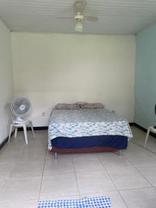 a bedroom with a bed and a fan and a tiled floor at Casa ao ar livre in Aracaju