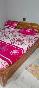 a bed with pink and white blankets and pillows at Tonton Love in Palimé