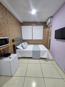 a bedroom with a white bed and a tv at Alice Suites in Arraial do Cabo +71 photos
