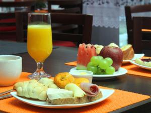 una mesa con platos de comida y un vaso de zumo de naranja en Vale Verde Palace Hotel, en Laranjal Paulista