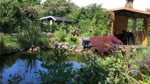 a garden with a pond and a gazebo at De Drie Populieren in Losser