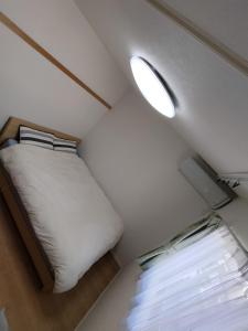 a small bedroom with a bed and a window at Guesthouse徳島201 in Tokushima