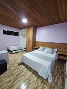 a bedroom with a large white bed and a television at Alice Suites in Arraial do Cabo