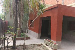 a red brick building with palm trees and plants at Casa Maipu in Corrientes