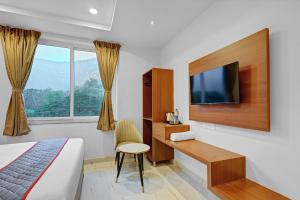 a bedroom with a bed and a desk and a tv at Hill Hara in Tirupati