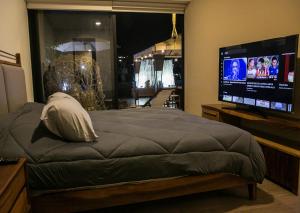a bedroom with a bed and a flat screen tv at Premium Apartment - Terraza Premium, Pool & Gym in Querétaro