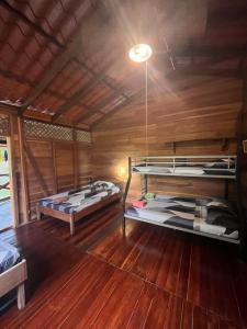 two beds in a room with wooden walls and wooden floors at Cocles House in Talamanca