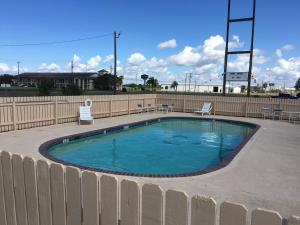 a small swimming pool with two chairs and a fence at Chaparral Motel in Port Lavaca
