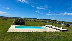 a pool with loungers and chairs next to a field at Chacra para 13! A 20min Punta del Este - Starlink in Maldonado