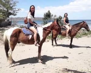 two women are riding horses on the beach at Monkey Houses in Matapalo