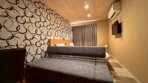 a bedroom with two beds and a wall at HOTEL THE POINT Kiyomizu Gojo in Kyoto