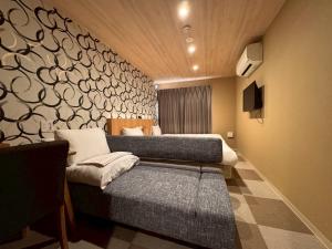 a bedroom with two beds and a wall with a mural at HOTEL THE POINT Kiyomizu Gojo in Kyoto