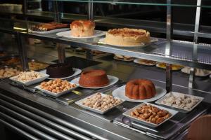a display case with different types of cakes and pastries at Hotel QualitySul in Teixeira de Freitas