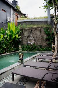 a swimming pool with two benches and a fountain at Goutama Homestay in Ubud