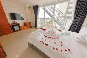 a bedroom with a white bed with a large window at Sea Light Hotel Nha Trang Beach in Nha Trang