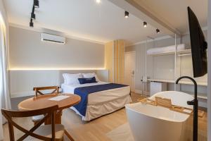 a bedroom with a bed and a table and a tub at Azurine Pousada in Passo de Torres