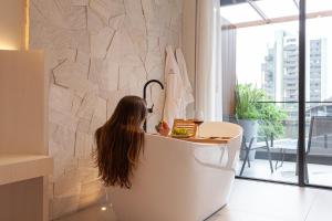 a woman sitting in a bath tub in a room at Azurine Pousada in Passo de Torres
