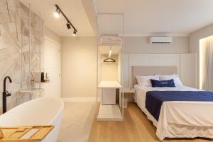 a bedroom with a bed and a tub in a room at Azurine Pousada in Passo de Torres