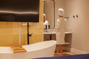 a woman in a bathroom with a tub and a sink at Azurine Pousada in Passo de Torres