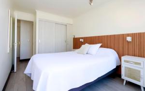 a bedroom with a white bed and a wooden wall at Playa Paraíso Resort in Concón +19 photos