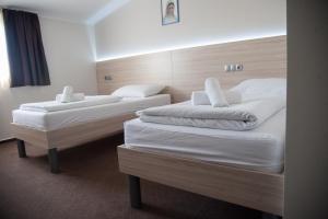 two beds in a hotel room with white sheets at Hotel Glorija in Međugorje