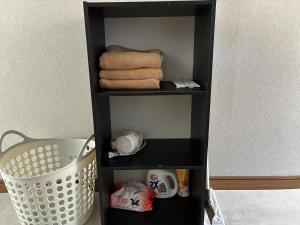 a black shelf with towels and a laundry basket at アルピエd 201号室 軽自動車無料駐車場Wi-Fiあります お部屋リフォーム済み in Kumamoto +6 photos
