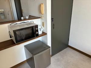 a microwave sitting on a shelf in a kitchen at アルピエd 201号室 軽自動車無料駐車場Wi-Fiあります お部屋リフォーム済み in Kumamoto