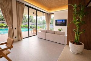 a living room with a white couch and a plant at AVA Radharani Villa in Wok Tum +10 photos