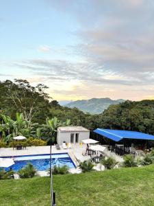 a resort with a pool and tables and chairs at Finca Villa Carmen, Vía Magdalena in Villeta