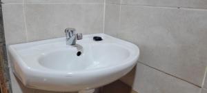 a white sink in a white tiled bathroom at Destiny Paradise in Amagoro