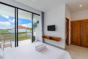 a bedroom with a bed and a balcony with a tv at Famiglie Guest House in Canggu