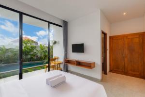 a bedroom with a bed and a tv and a balcony at Famiglie Guest House in Canggu +17 photos