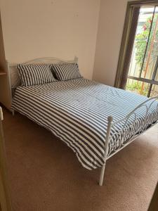 a bed with a black and white striped comforter and a window at Echucas Pawfect Accommodation - Dog Friendly in Echuca +11 photos