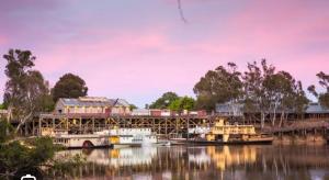 a train on a bridge over a river with boats at Echucas Pawfect Accommodation - Dog Friendly in Echuca