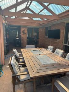 a large wooden table with chairs and a television at Echucas Pawfect Accommodation - Dog Friendly in Echuca