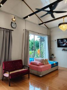 a living room with a bed and a couch and a window at Kampung Cottage Bagan Datuk in Selekoh
