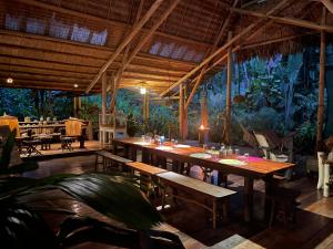 a restaurant with a large wooden table and benches at Maravilla Ojo Del Mar Naturelodge in Puerto Jiménez